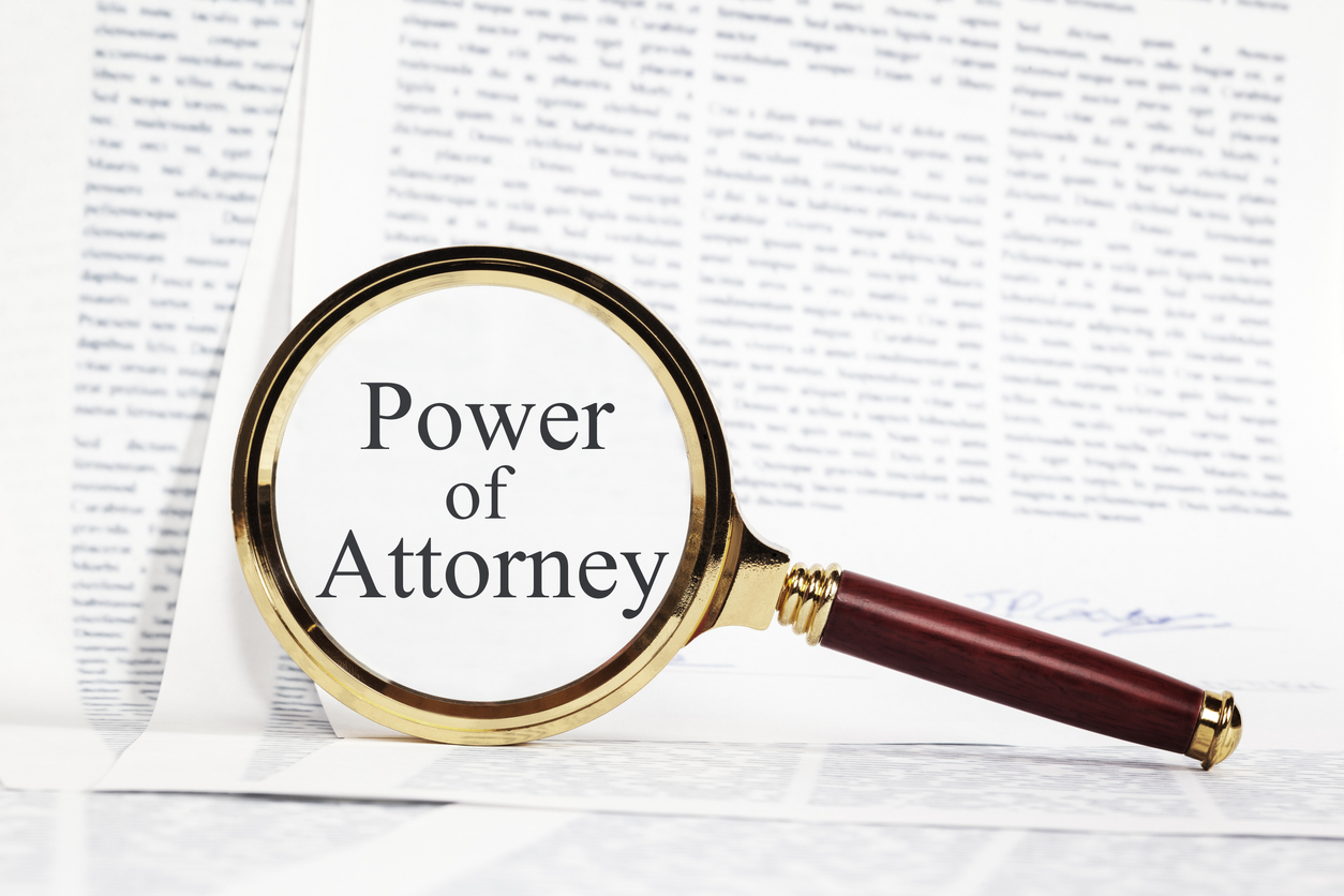 Power of Attorney written inside a magnifying glass in front of documents